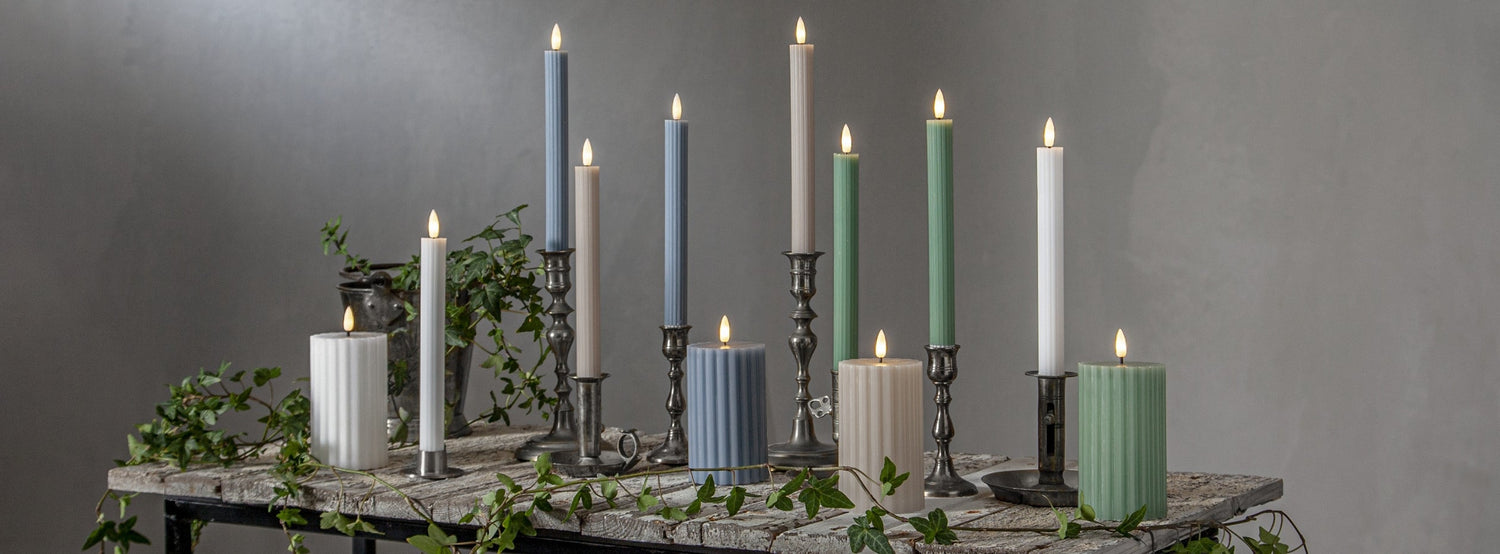 Stripe LED gyertya kollekció különböző méretű és színű valódi viaszból készült kannelúrás gyertyákkal, vintage gyertyatartókban elhelyezve, meleg fényű LED lánggal.