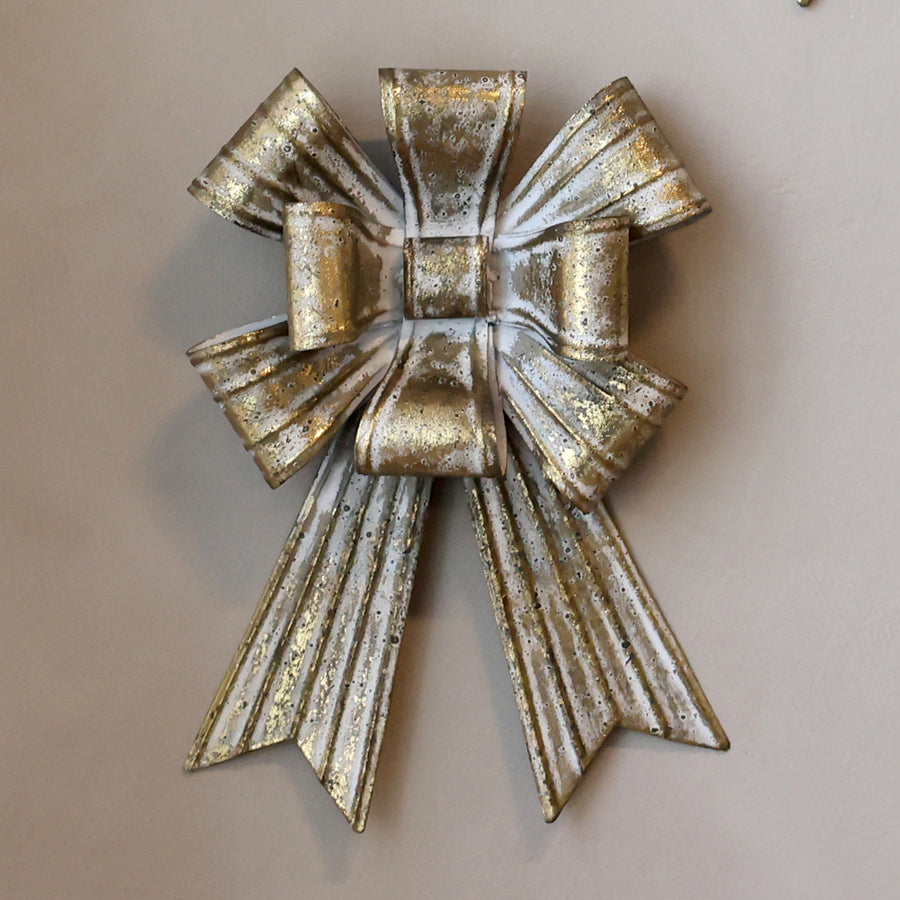Art Ferro antique copper metal Christmas bow with cream patina, 25 cm tall, mounted on a wall.