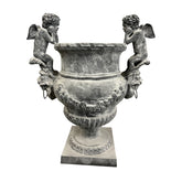 Antikolt öntöttvas díszkaspó könyöklő puttófigurákkal és klasszikus ornamentikával, Château Jardin kollekció, 100 cm magas.