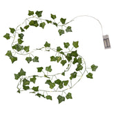Zöld színű, 200 cm hosszú, 20 meleg fehér LED-es fényforrással ellátott, elemes működésű mű borostyán girland időzítő funkcióval, fehér háttér előtt elhelyezve.