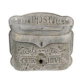 Antik hatású, szürke fém postaláda dombornyomott mintával és „Welcome to our hive” felirattal.