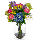 Vegyes művirágokból készült nagy virágcsokor, áttetsző üvegvázában.