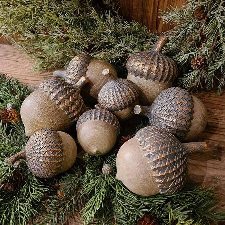 Vintage, rusztikus stílusú, 14 cm magas, fa hatású, antik arany színnel patinázott karácsonyi makk díszek fenyők között