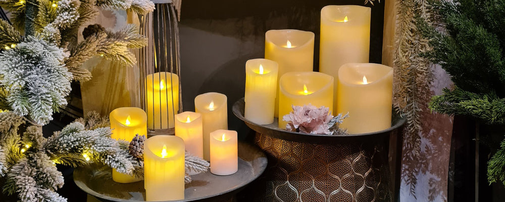 LED gyertyák sokasága, fémtálcákon fenyőfaágakkal.