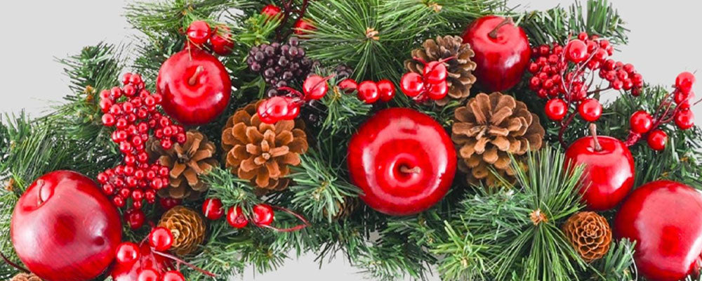 Piros almával, piros bogyókkal és tobozokkal díszített karácsonyi koszorú.