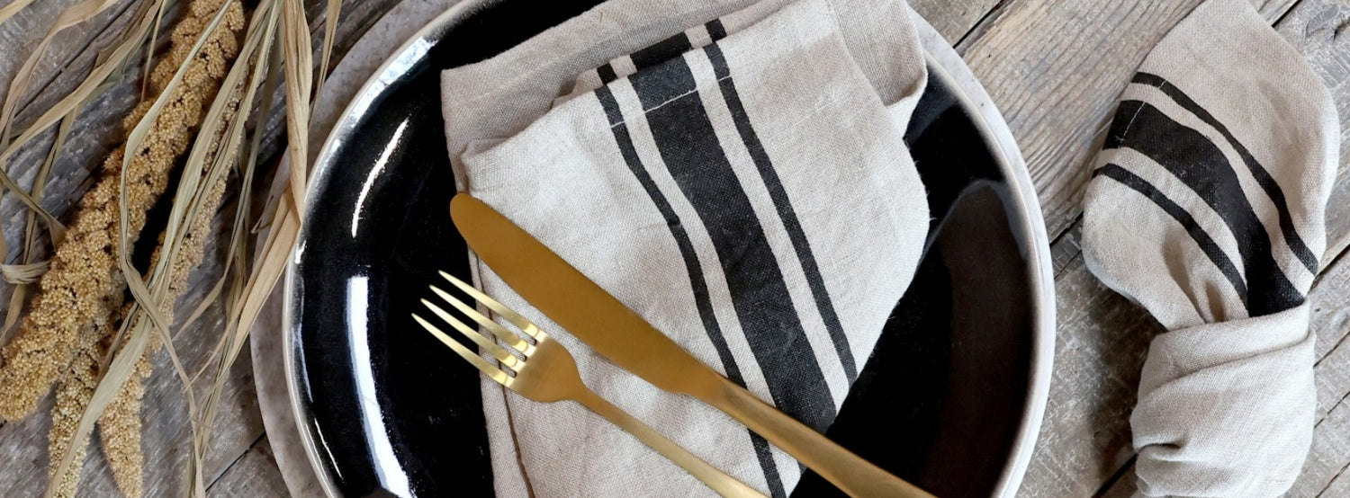 Fekete csíkos textil szalvéta arany evőeszközzel.