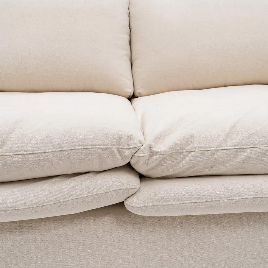 Bézs színű pamutvászon kárpitozású, kényelmes párnákkal ellátott kortárs kanapé..