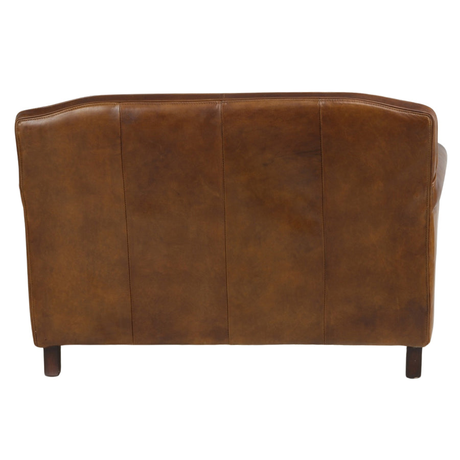 Hátsó háromnegyedes nézet a vintage bőrkanapéról, jól látható ívelt formák és sötét fa lábak.