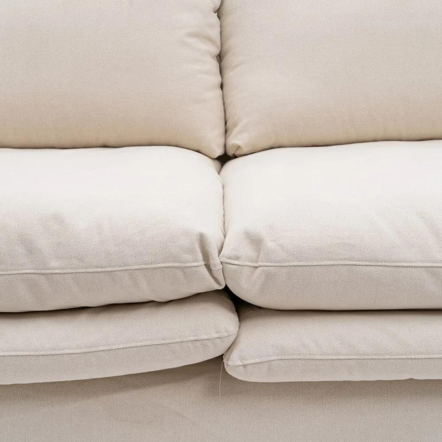 Bézs színű pamutvászon kárpitozású, kényelmes párnákkal ellátott kortárs kanapé.