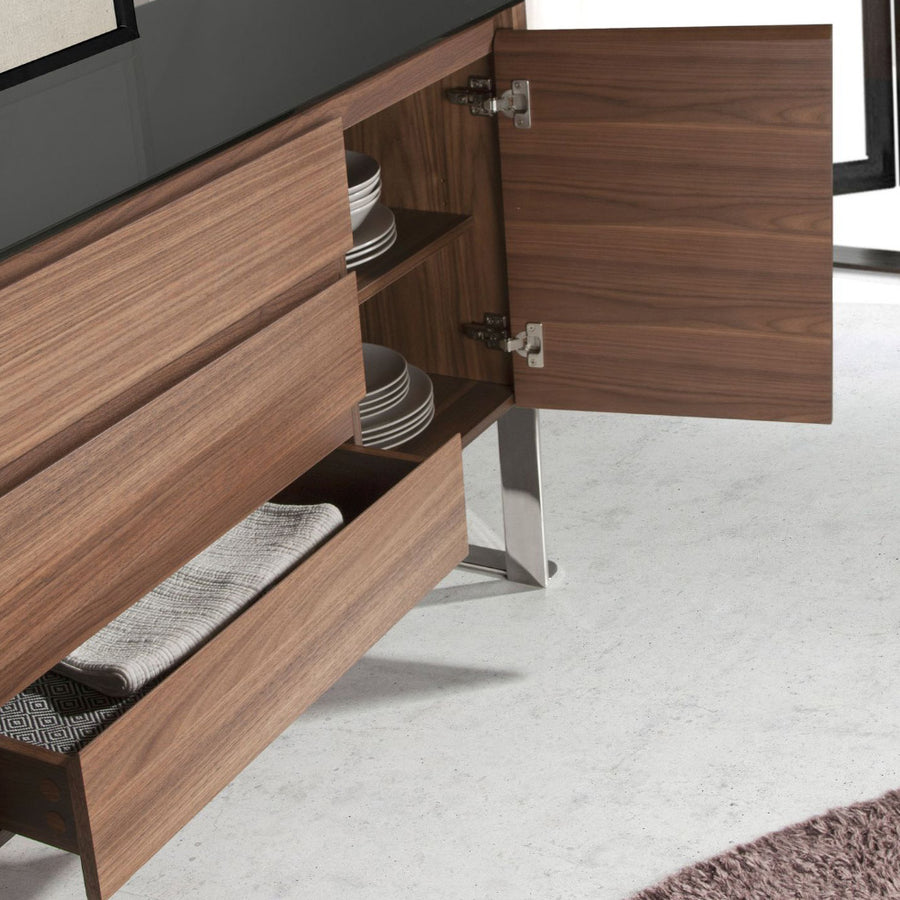 Kortárs stílusú, diófa furnérral borított, dizájn komódszekrény fekete edzett üveg fedlappal.