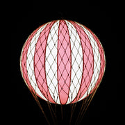 A piros-bézs színű LED-es hőlégballon fénye sötétben.