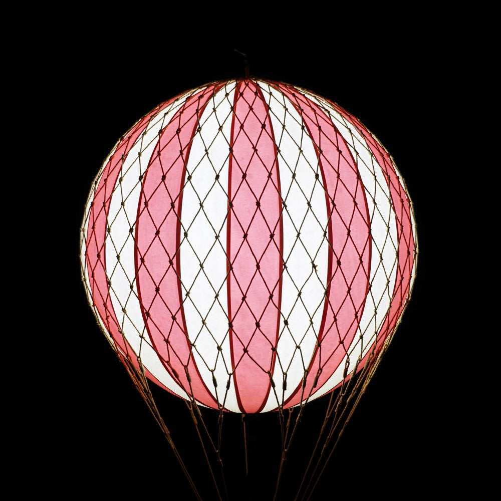 A piros-bézs színű LED-es hőlégballon fénye sötétben.