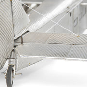 Fémből készült, részletgazdag, ezüstszínű Ford Trimotor repülőgép-modell állványon