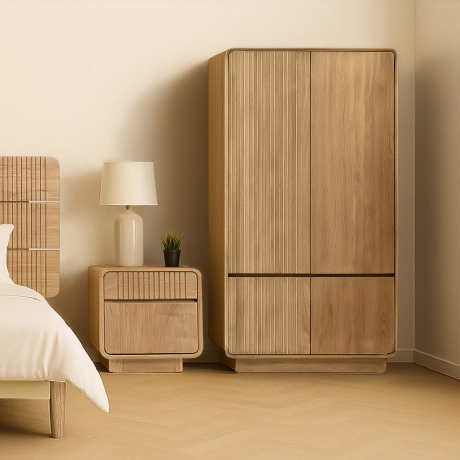 Natúr színű Eyre teakfa gardróbszekrény és éjjeliszekrény modern, világos hálószobai enteriőrben, lámpával és dekorációval.