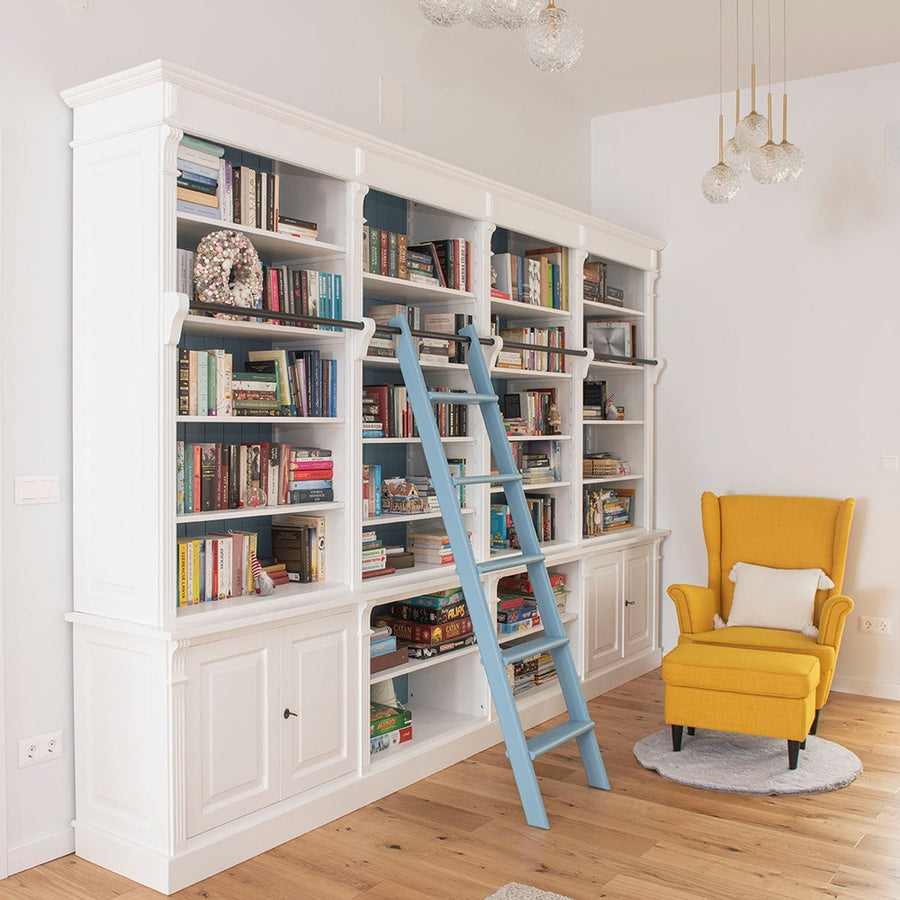 Egyedi tervezésű, fehér színű könyvszekrény, kék létrával.
