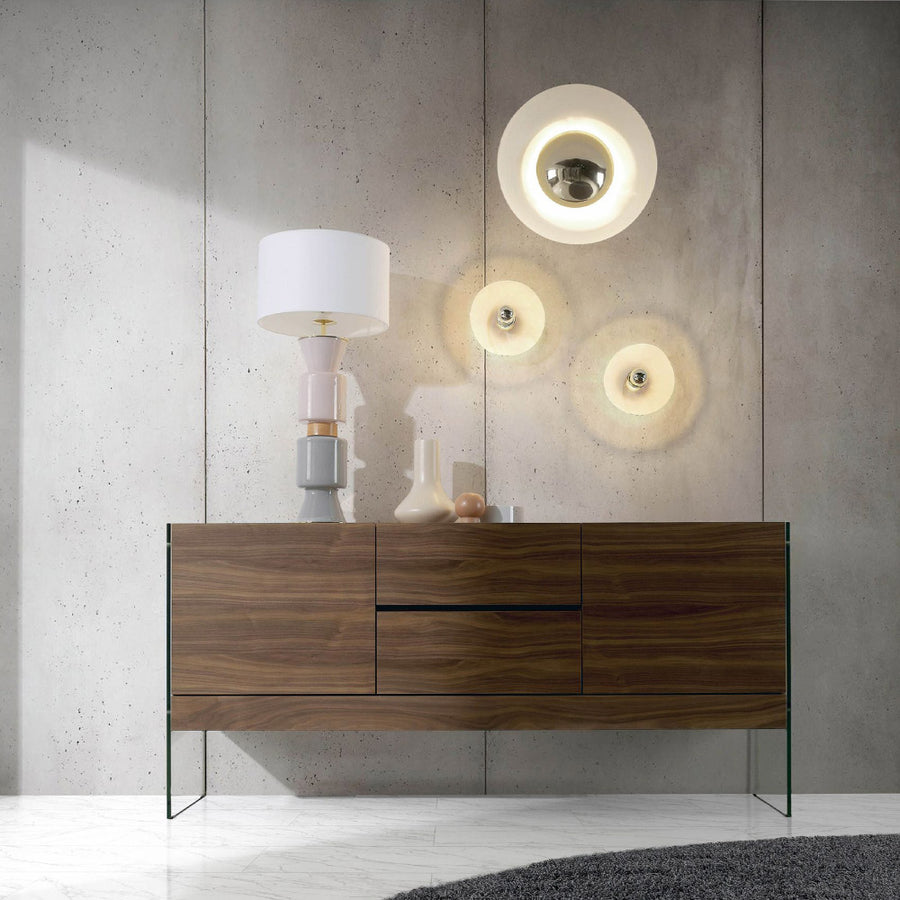 Kortárs stílusú, diófa furnérral borított, dizájn komódszekrény edzett üveg lábakkal.