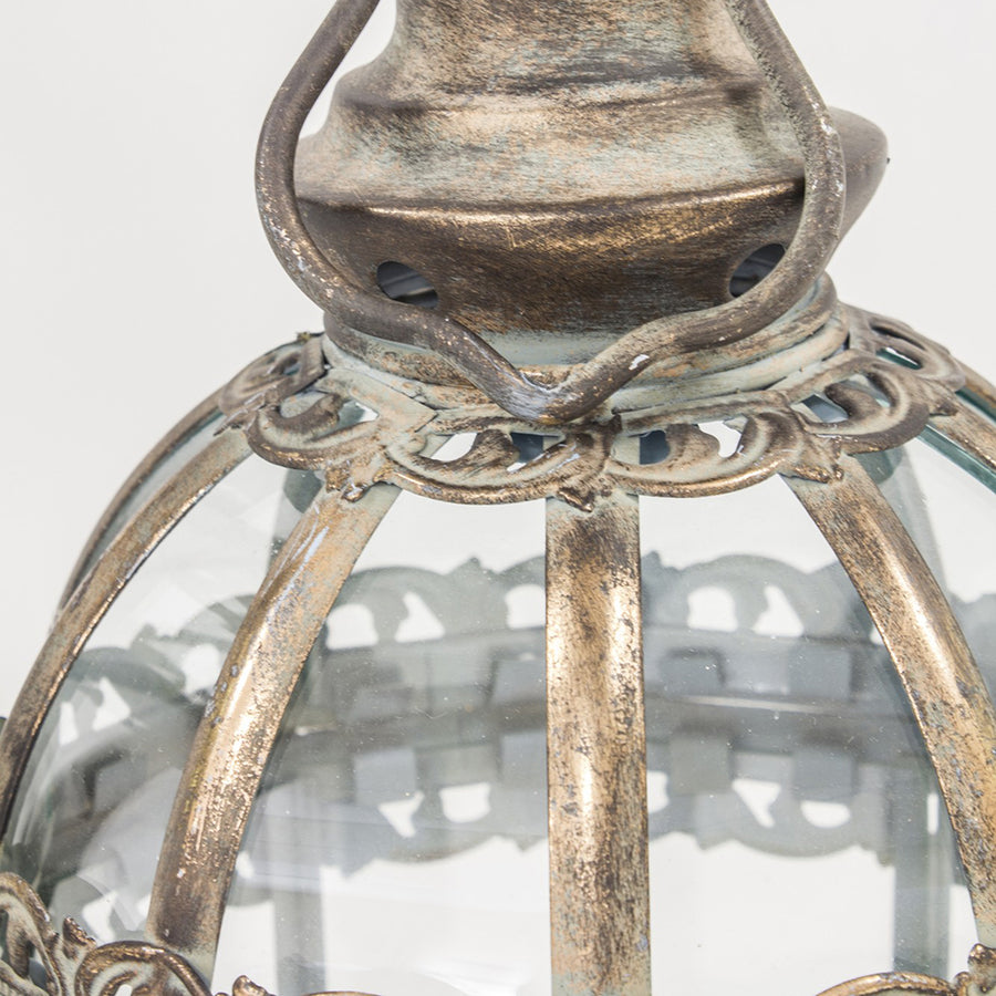 Antikolt aranyszínű fém lámpás kupola részének részletfotója díszített peremmel és akasztóval