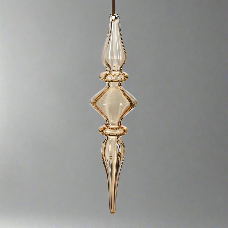 Modern, mégis klasszikus megjelenésű borostyánsárga üveg karácsonyfadísz, elegáns csavart formában.