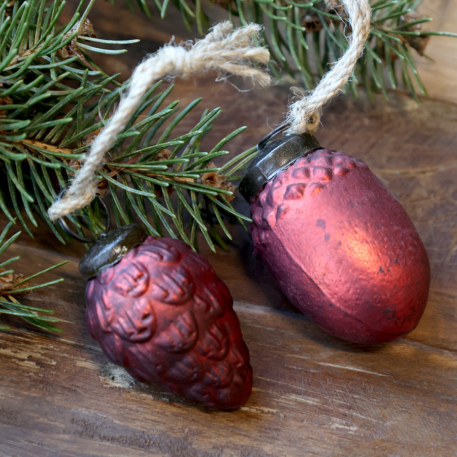 Toboz és makk formájú antik meggybordó karácsonyfadíszek juta akasztóval, fenyőág mellett