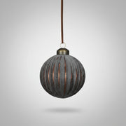 Barázdált mintájú, bronzbarna Antique üveg karácsonyfadísz közelről, selyem szalaggal felfüggesztve.