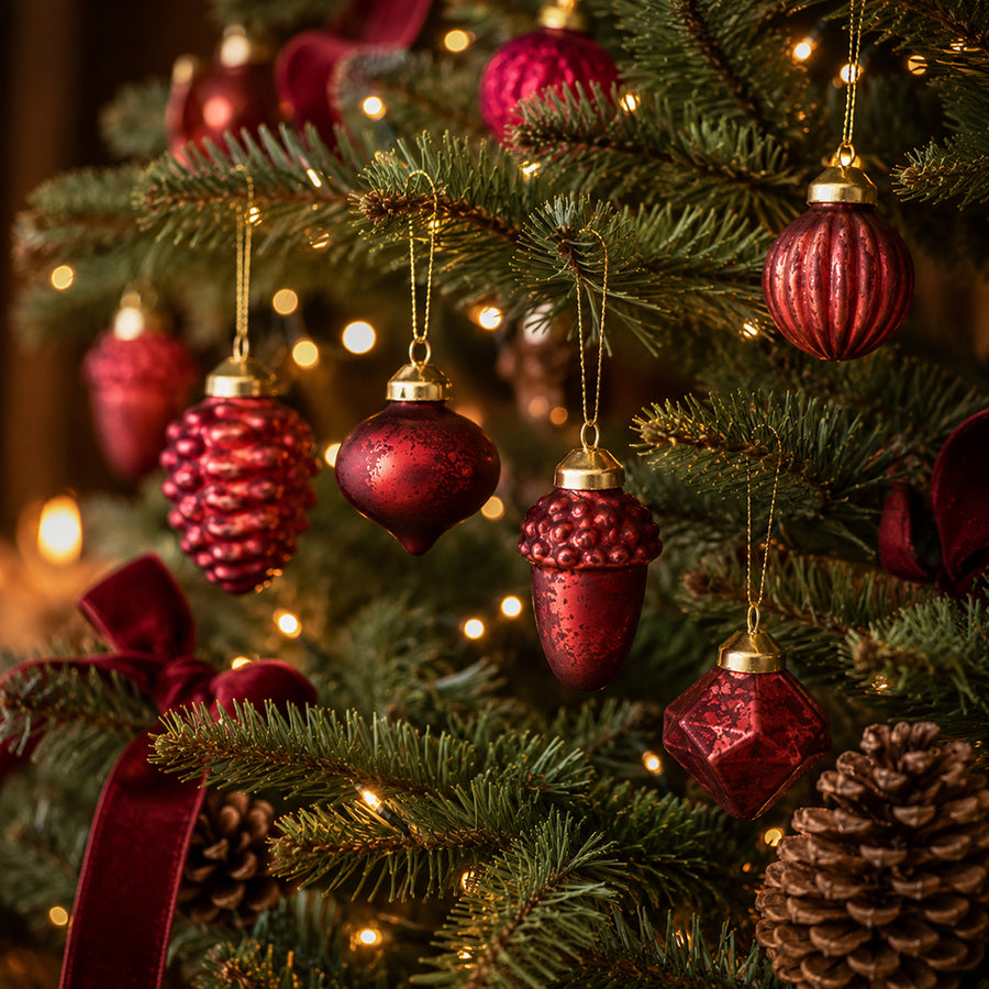 Antik bordó üveg karácsonyfadíszek fenyőfán meleg fényfüzérrel és bordó bársonyszalaggal