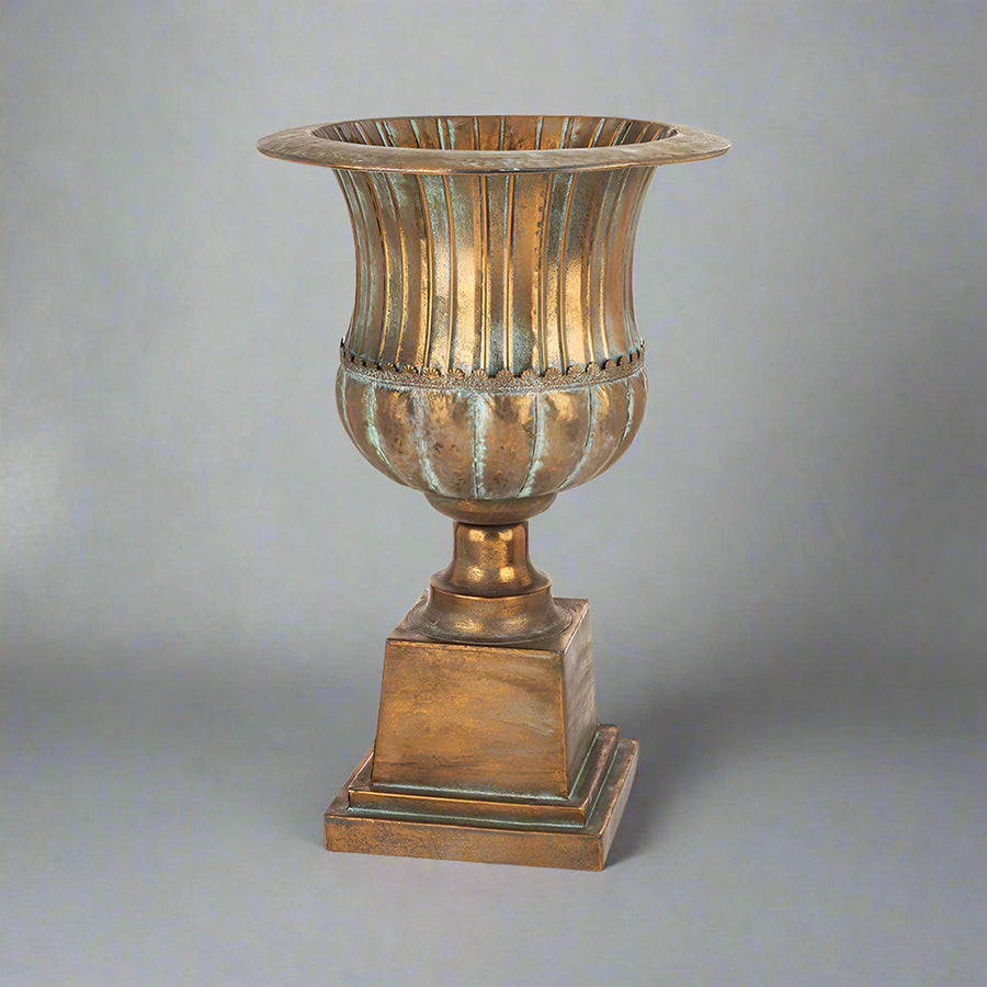 Antique Metals klasszikus stílusú, antik rézszínű fém kaspó teljes magasságban, patinázott felülettel és díszes talapzattal.