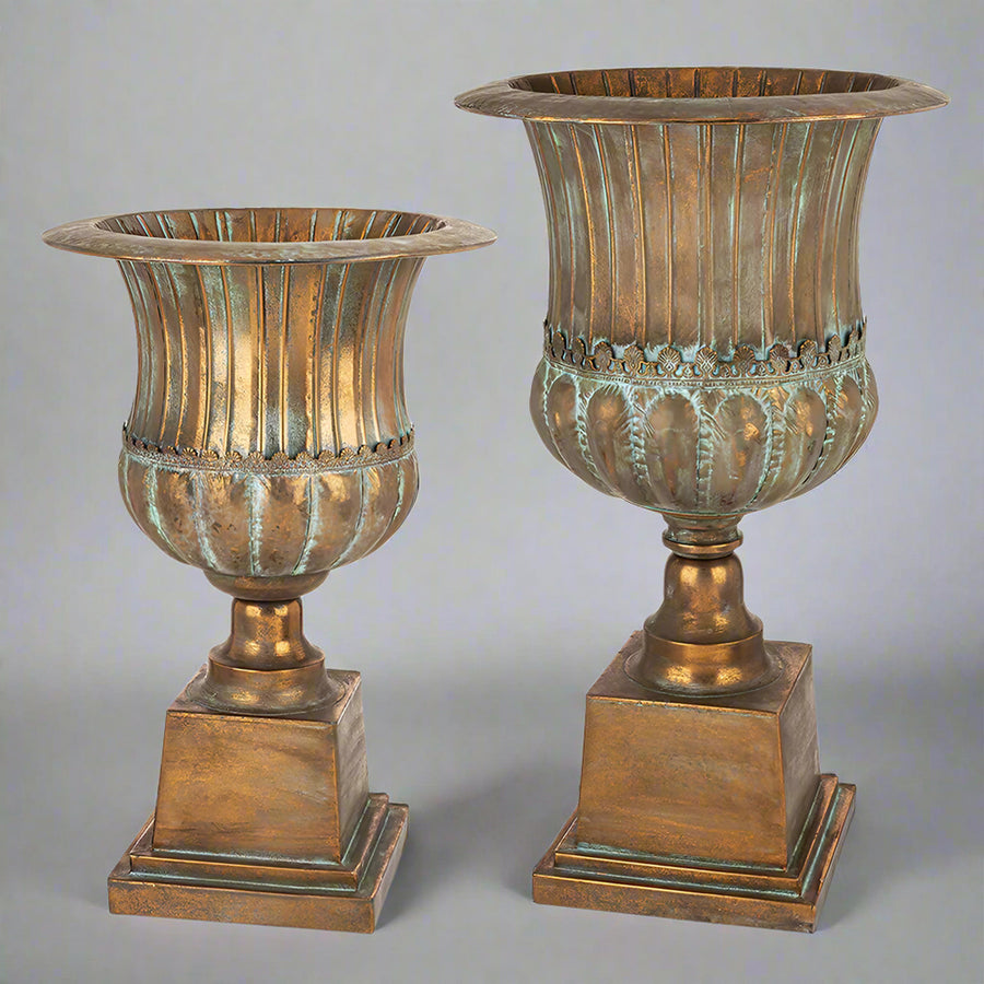 Két Antique Metals kaspó különböző méretben, antik rézszínű patinázott fém felülettel és klasszikus urnás formavilággal.