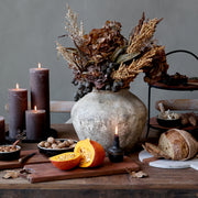 Antik váza őszi hangulatú dekorációval, gyertyákkal és sütőtökkel megterített asztalon.