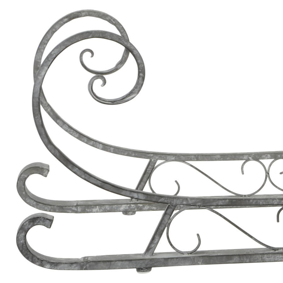 Fém dekor szán elülső részlete ívelt csővázzal, patinás felülettel és díszes vonalvezetéssel.