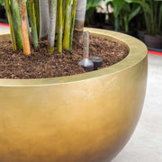 Közeli kép a kaspó pereméről és az automata öntözőrendszerről beültetett növények mellett.