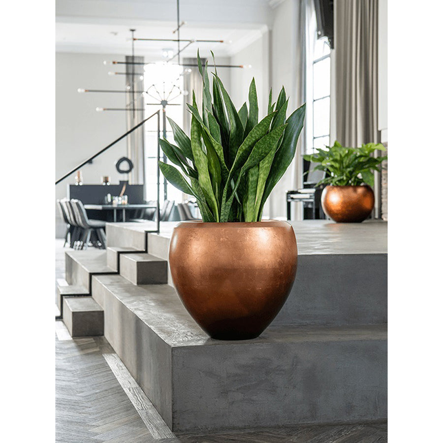 Modern nappaliban elhelyezett BAQ Metallic Couple matt réz kaspó zöld szobanövénnyel.