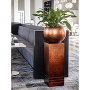 BAQ réz színű kaspó beltéri enteriőrben, növénnyel dekorálva egy modern padlón.