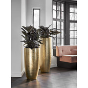 Fényes arany kaspók modern enteriőrben, sötét levelű növényekkel beültetve