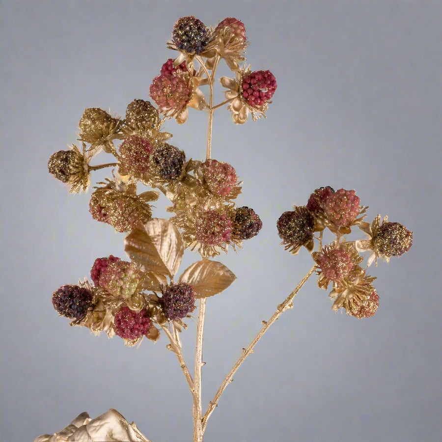Részletfotó aranyszínű mű szeder ágról, bordó és arany bogyókkal, csillogó díszítéssel.
