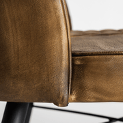 Közelkép a karamell színű bőrkárpit ívelt széléről, precíz varrással.