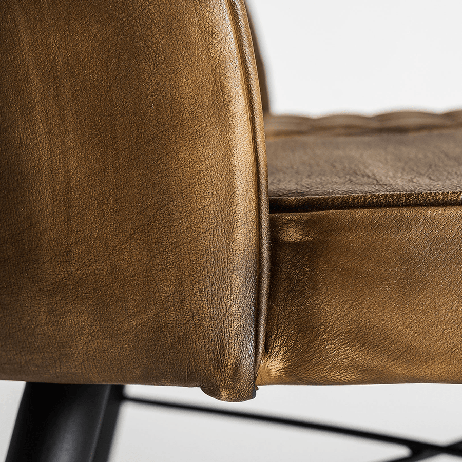 Közelkép a karamell színű bőrkárpit ívelt széléről, precíz varrással.