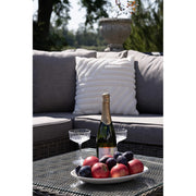 Közeli kép a Calvi lounge szett dohányzóasztaláról, gyümölcsökkel és pezsgővel.