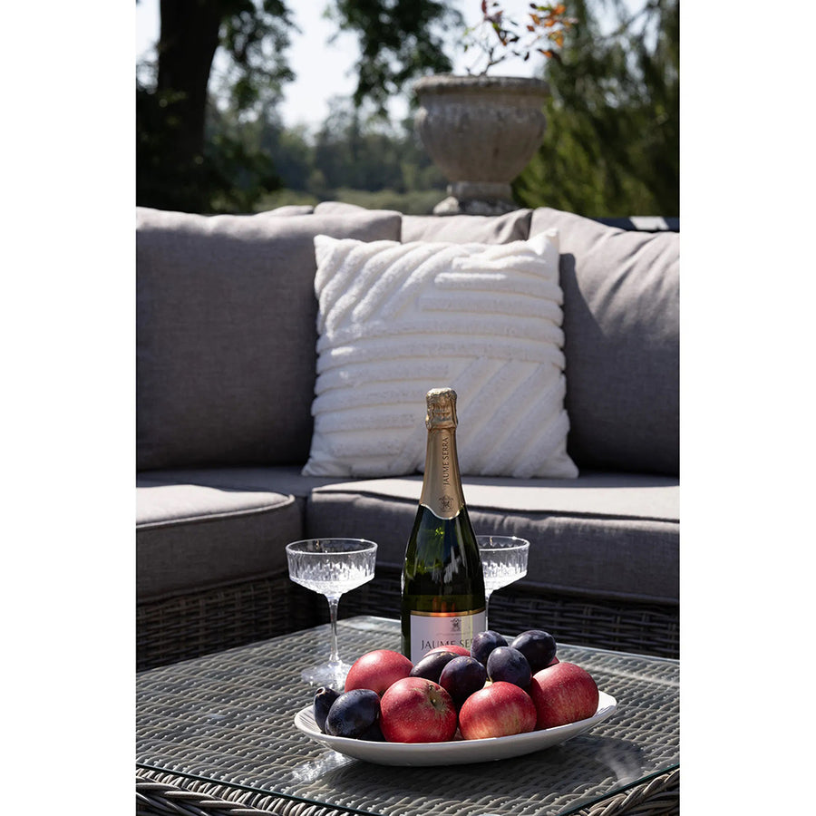 Közeli kép a Calvi lounge szett dohányzóasztaláról, gyümölcsökkel és pezsgővel.