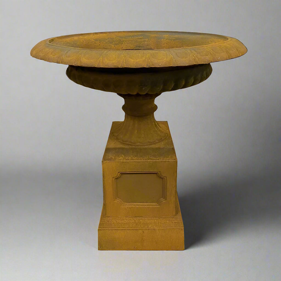 Antikolt felületű öntöttvas kaspó posztamensen, oldalsó nézetben, Château Jardin kollekció, klasszikus kerti dekorációként.