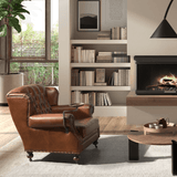 Chester konyakbarna bőrfotel könyvespolc mellett, kandallóval a háttérben