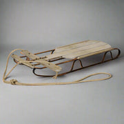 Karácsonyi dekor szánkó stúdiófotón, antikolt fa felülettel és fém talpazattal.