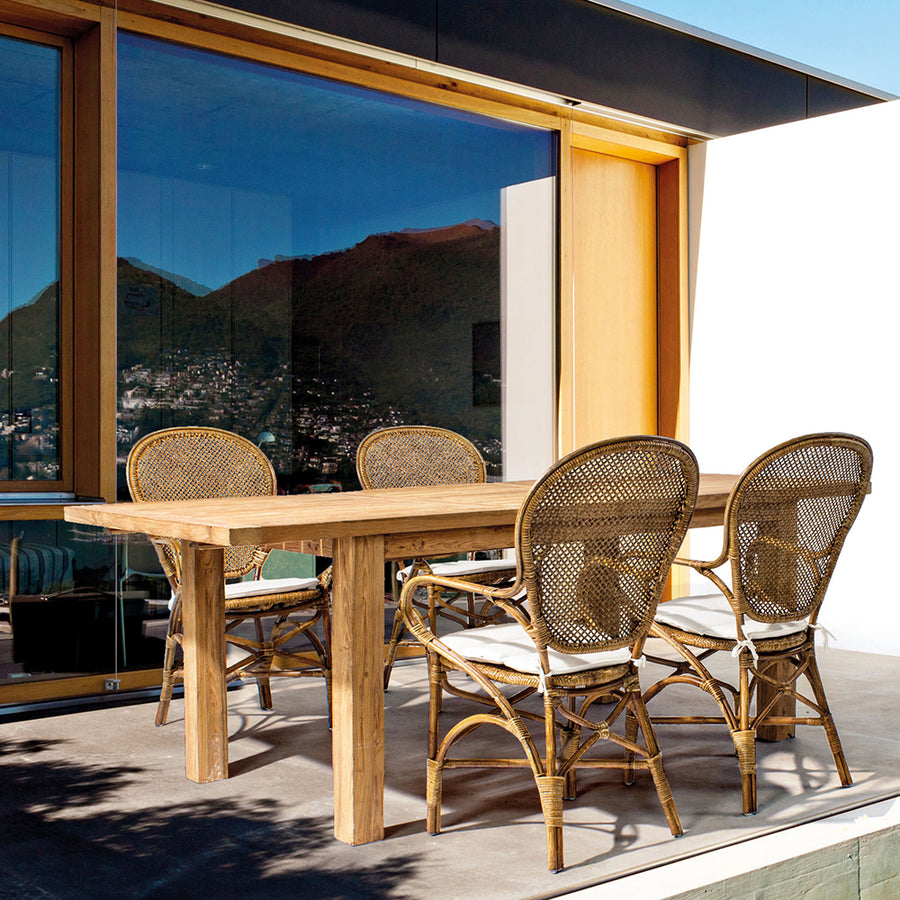 Mézbarna rattan székek kültéri elrendezésben, fa étkezőasztallal kombinálva.