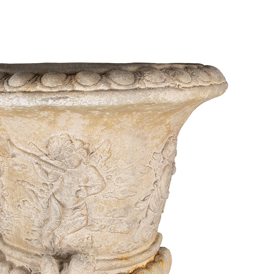 Közelkép az antik hatású kaspó angyaldíszítéséről és a bézs felület finom textúrájáról