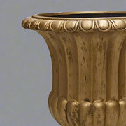 Közelkép az aranyszínű kaspó peremének antikolt díszítéséről