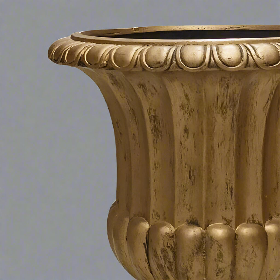 Közelkép az aranyszínű kaspó peremének antikolt díszítéséről