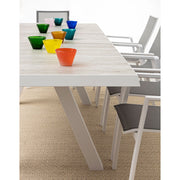 Krém színű kortárs kerti étkezőasztal színes üvegpoharakkal.