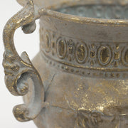 Aranyszínű, serlegformájú fémkaspó dekoratív fülekkel.