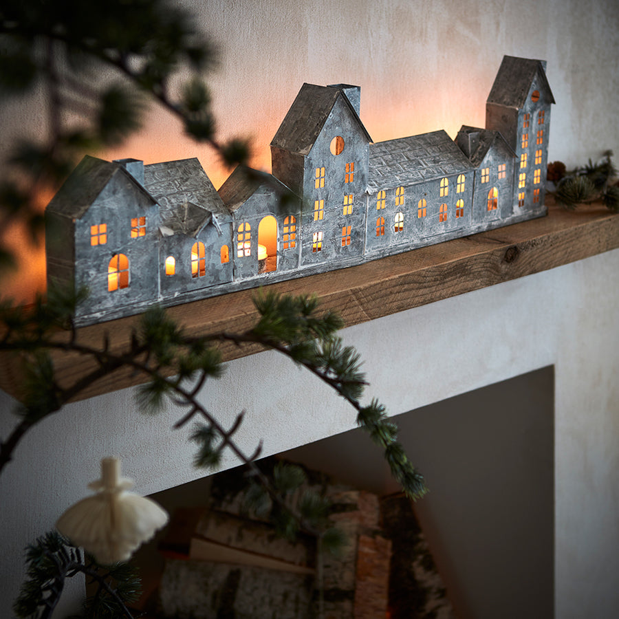 Szürke színű, bádogból készült házikókat formázó lámpás.