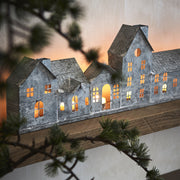 Szürke színű, bádogból készült házikókat formázó lámpás.