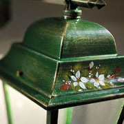 Közelkép a Ferroluce Gorizia lámpa antikolt zöld tetőrészéről kézzel festett fehér virágmintával, finom arany árnyalatokkal.